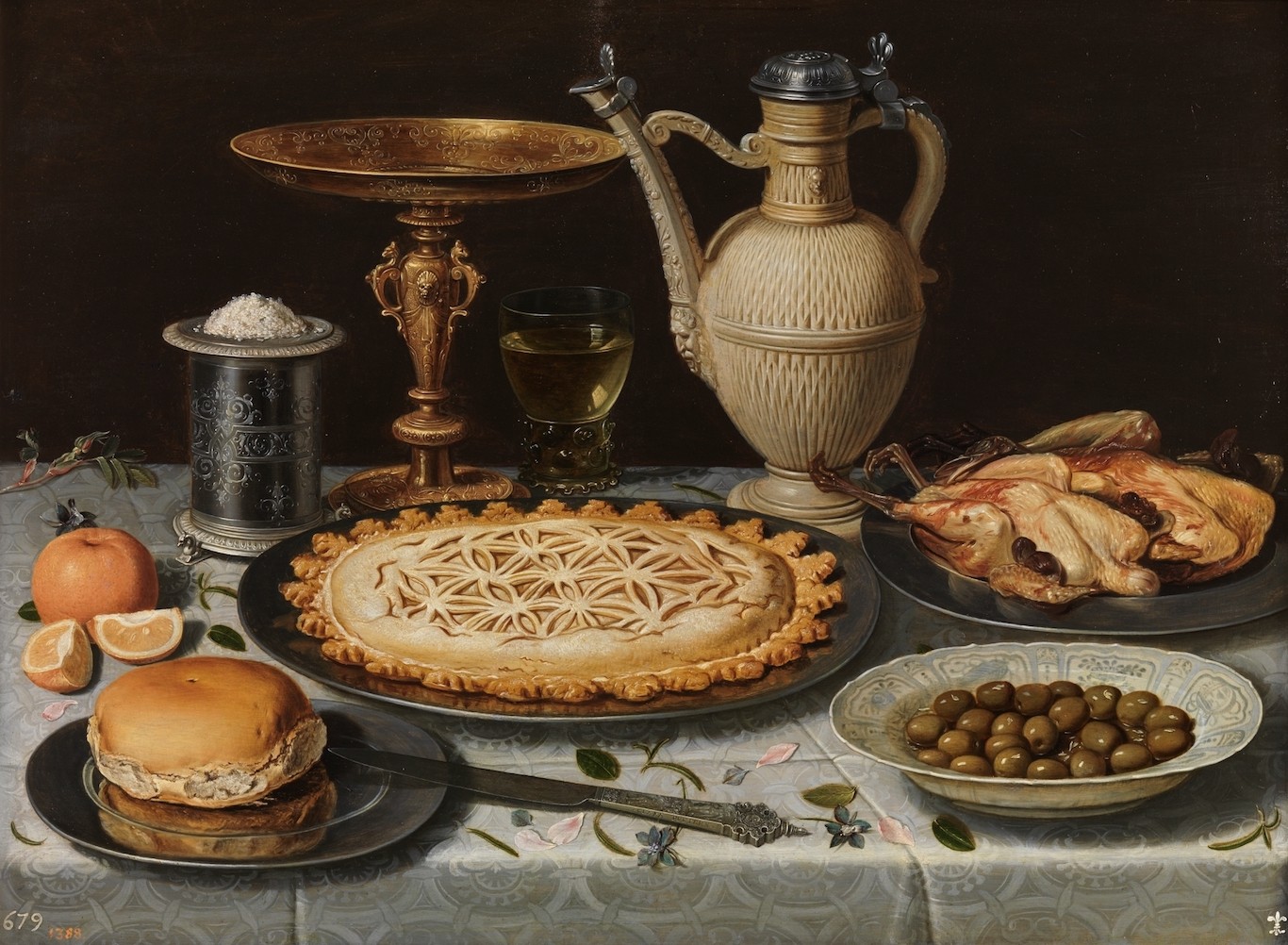 Mesa_con_mantel_salero_taza_dorada_pastel_jarra_plato_de_porcelana_con_aceitunas_y_aves_asadas.jpg